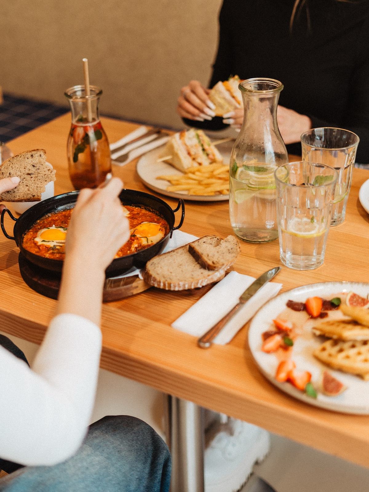 Plný stůl u nás: shakshuka v pánvi, kváskový chléb, sendvič s hranolky a vafle s jahodami